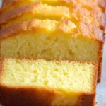 Quatre Quart Recette : Quatre quart moelleux et doré, tranché et présenté sur une assiette simple, parfait pour un dessert facile à réaliser.